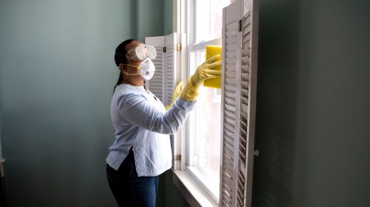disinfection - woman in white long sleeve shirt and blue denim jeans standing beside white wooden framed glass