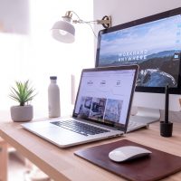 digital marketing MacBook Pro on table beside white iMac and Magic Mouse