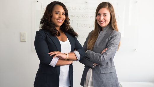 successful entrepreneur two women in suits standing beside wall