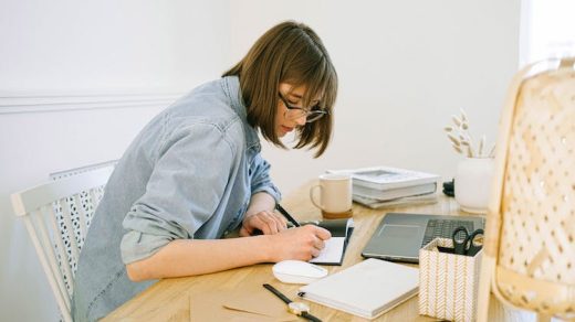 Woman sitting at a desk with a laptop and a notebook