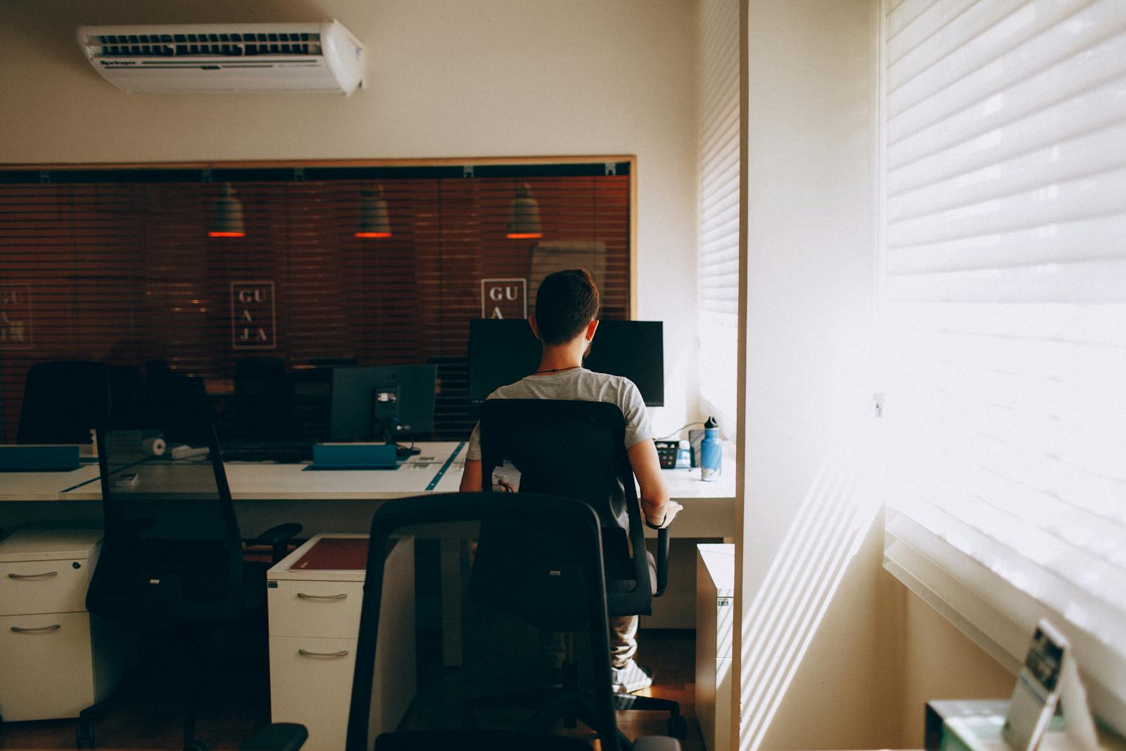 Person in Gray Shirt Sitting on Computer Chair