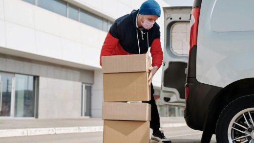 A man wearing a face mask and carrying boxes