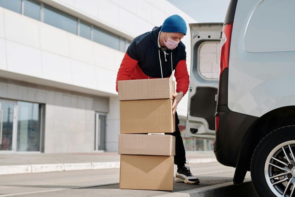 A man wearing a face mask and carrying boxes