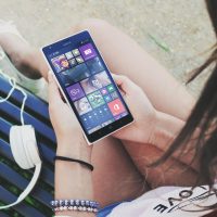 Woman Holding Turned Smartphone While Sitting on Bench Close-up Photography