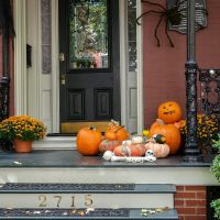 a front porch decorated for halloween with pumpkins and gourds