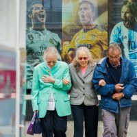 two women and man walking in the street during daytime