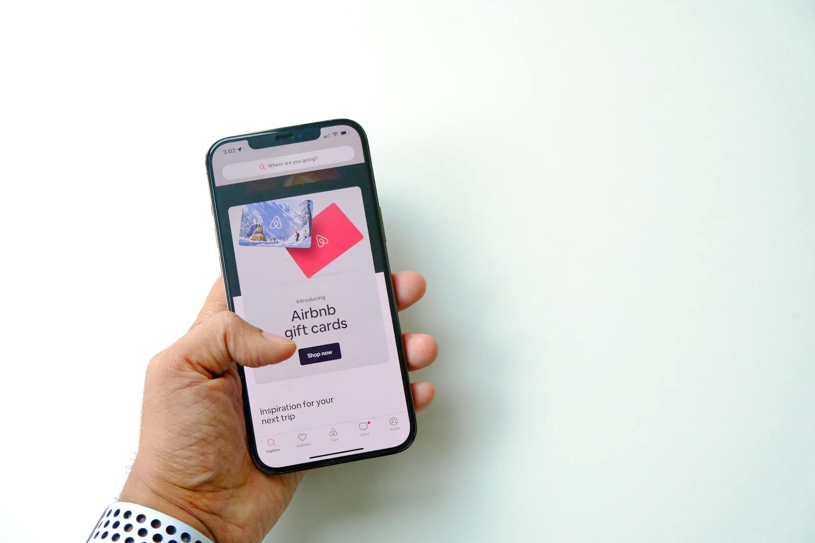 Close-up of a Man Holding a Smartphone Displaying a Shop with Airbnb Gift Cards