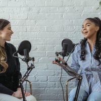 Smiling African American female guest gesticulating while having interview with journalist sitting near mic