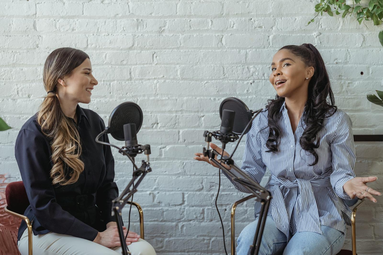 Smiling African American female guest gesticulating while having interview with journalist sitting near mic